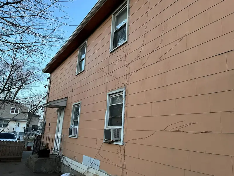 Two-story house with faded, cracked siding along the side, Hempstead, NY